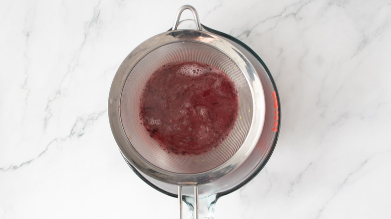 Cranberry juice sitting in mesh strainer