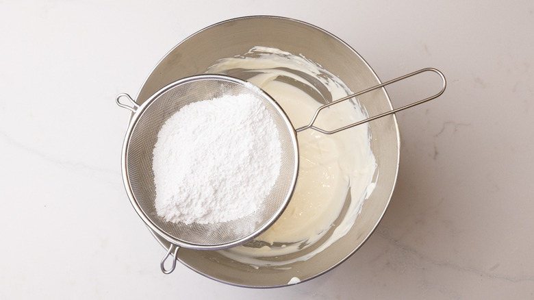 sifting confectioners sugar into bowl
