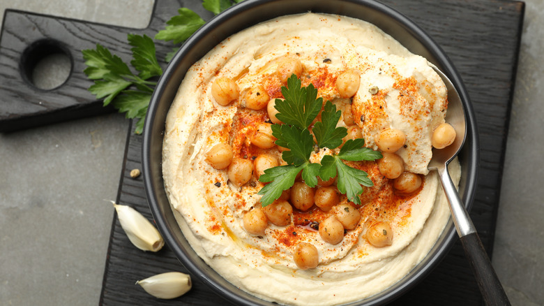Bowl of hummus with whole chickpeas on cutting board
