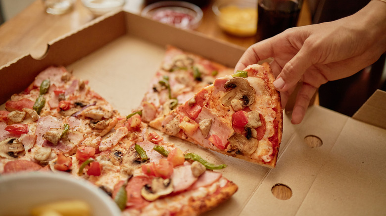 Hand taking pizza from box