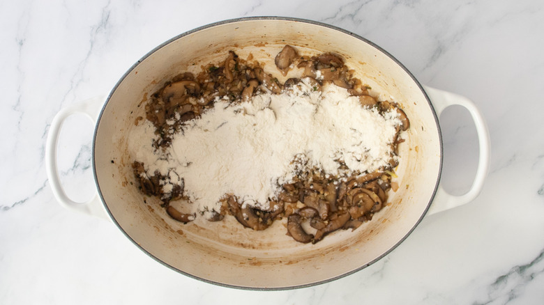 Dutch oven with sauteed mushrooms sprinkled with flour