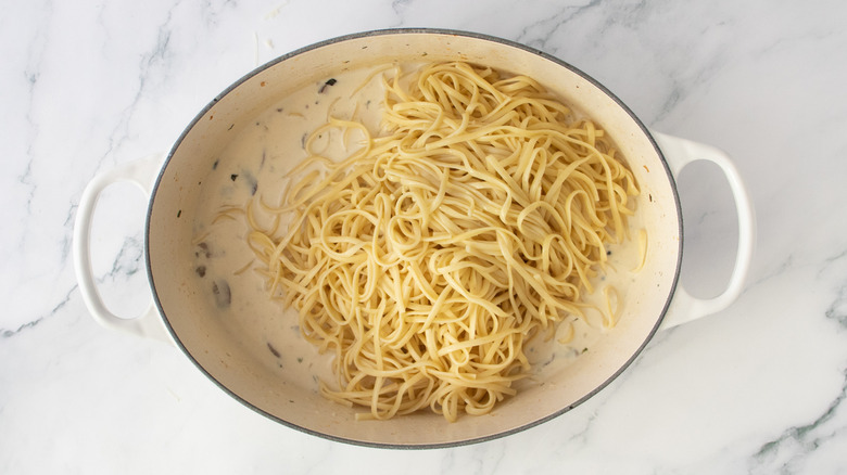 Dutch oven with mushroom cream sauce and cooked linguine