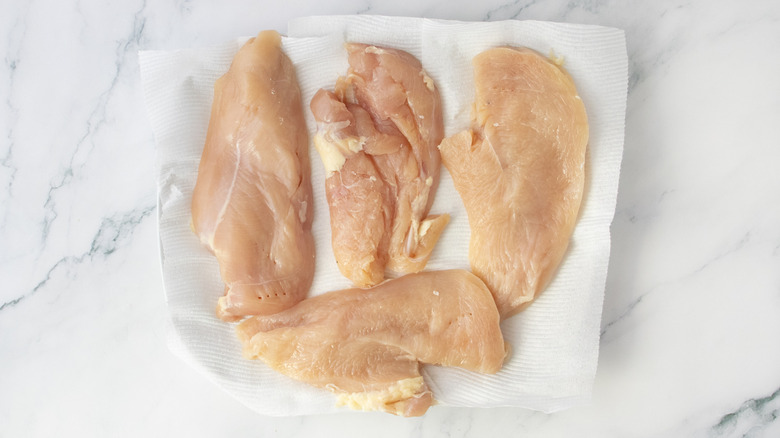 Raw chicken breasts on a plate with paper towels