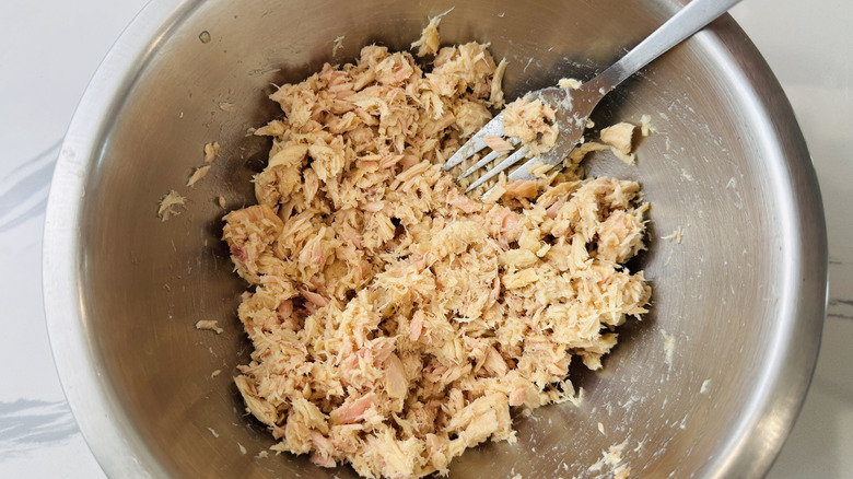Shredded canned tuna in stainless steel bowl with fork inside