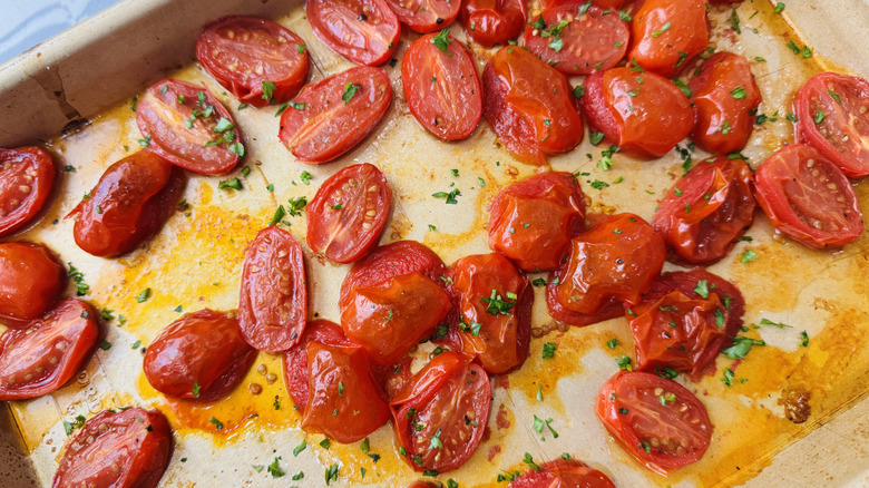 Roasted tomatoes sprinkled with fresh parsley on baking sheet