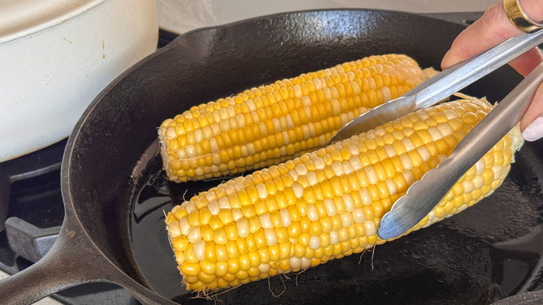 hand adding corn to skillet
