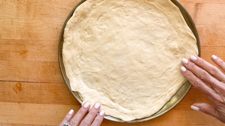 hands pressing dough in pan