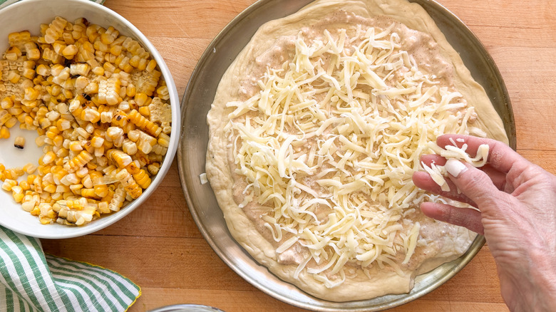 hand adding mozzarella to dough