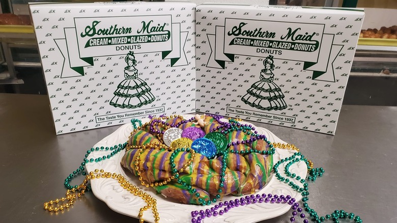 two white Southern Maid Donuts boxes behind a decorated King Cake