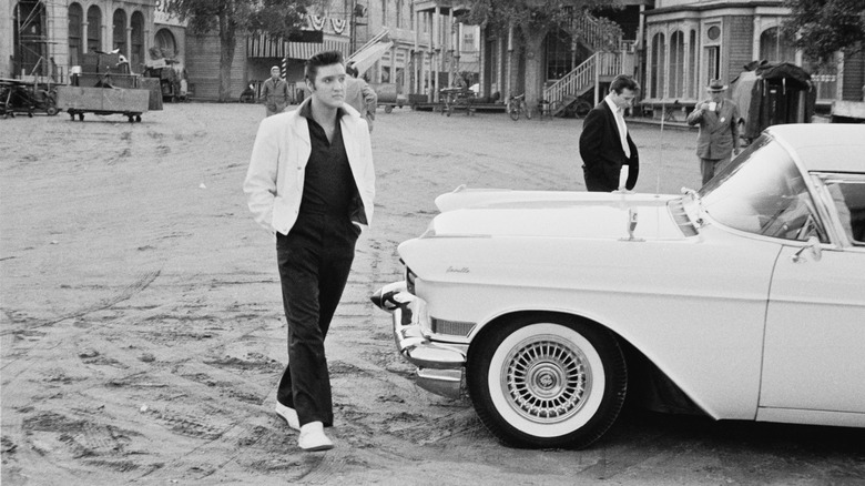 Elvis walking by a Cadillac