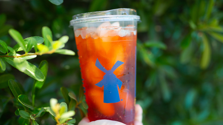 Hand holding an iced Dutch Brothers drink in the brand's signature cup design.