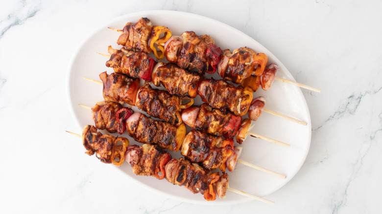 Grilled barbecue skewers on a large white platter