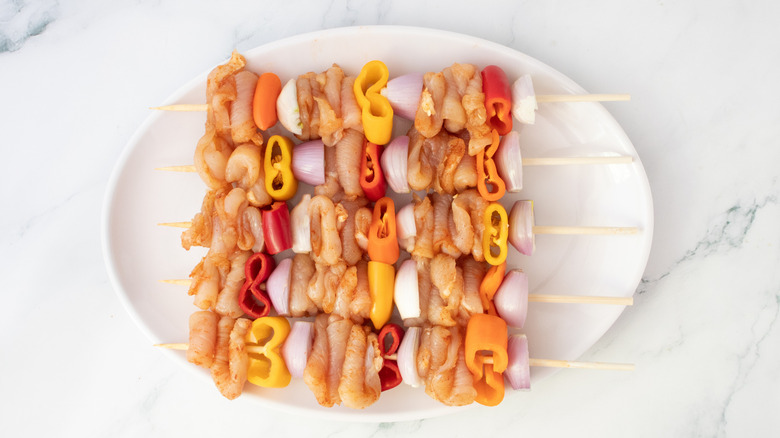 Raw chicken and vegetables threaded onto bamboo skewers