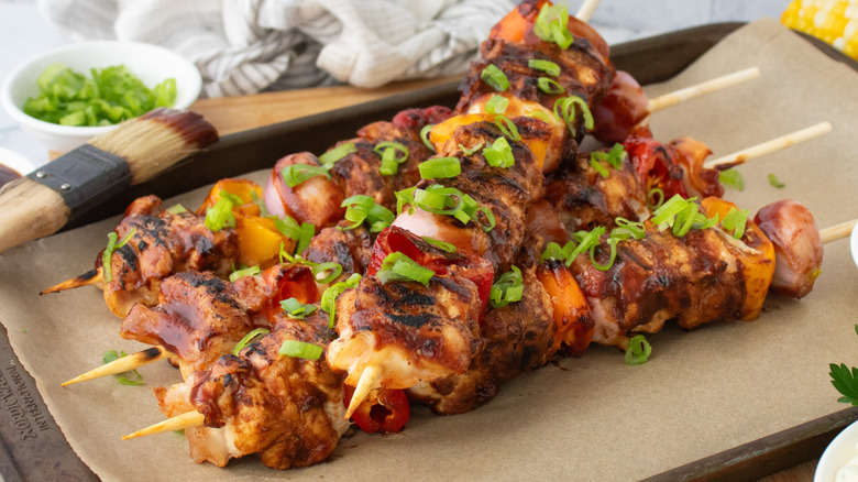 Side shot of grilled barbecue chicken skewers on a baking sheet