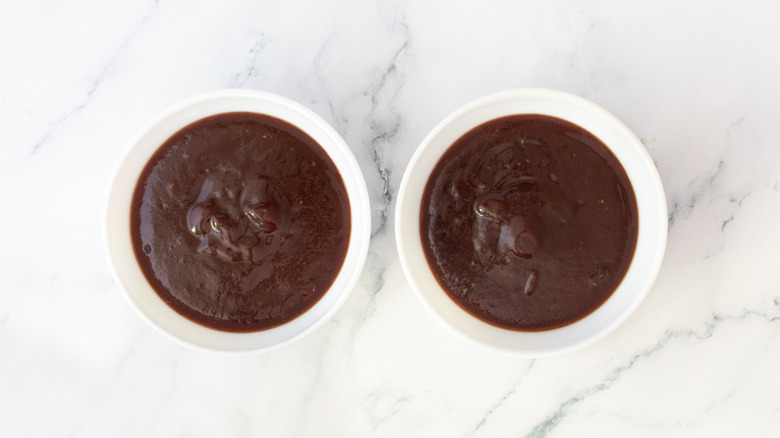 Two portions of barbecue sauce in small white bowls