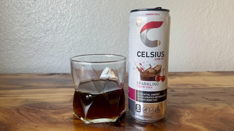 Can and glass of Sparkling Cherry Cola Celsius on a wooden tabletop