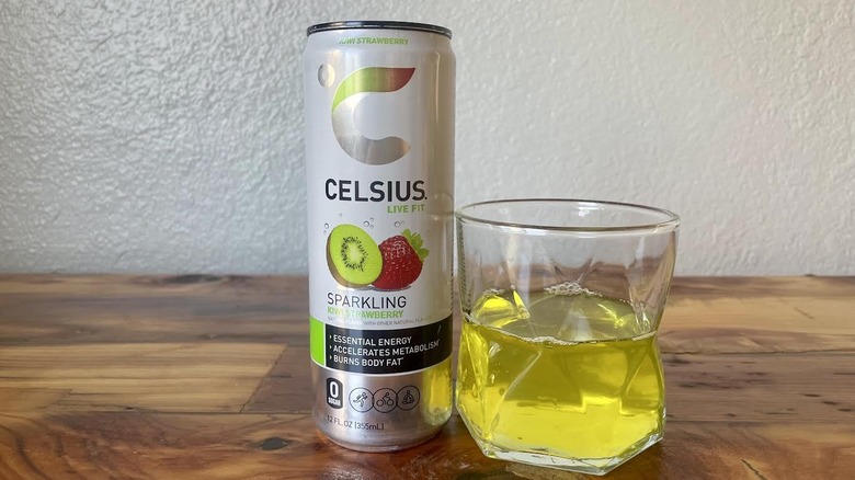 Can and glass of Sparkling Kiwi Strawberry Celsius on a wooden tabletop