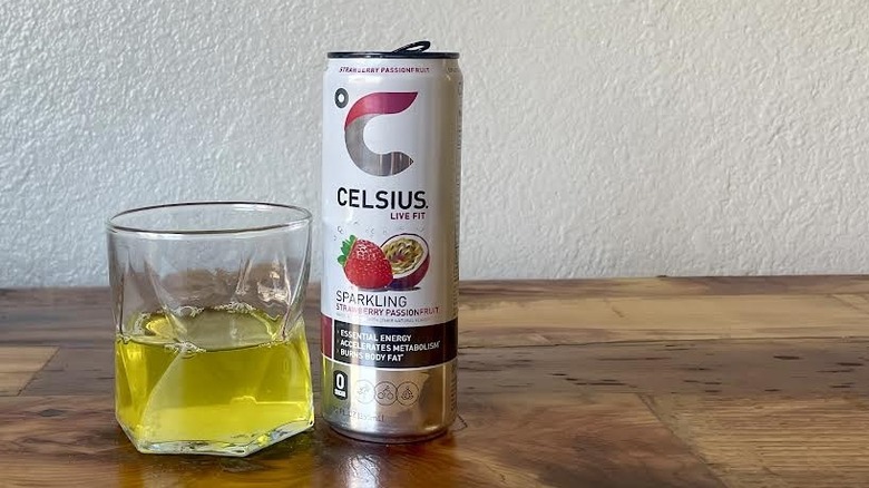 Can and glass of Sparkling Strawberry Passionfruit Celsius on a wooden tabletop