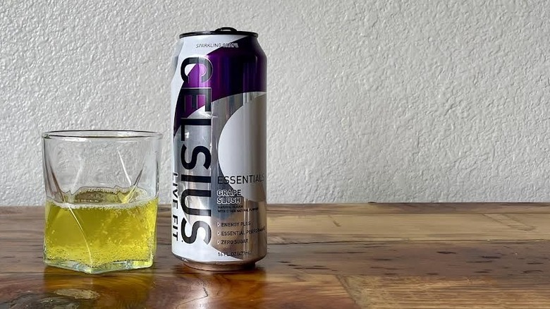 Can and glass of Essentials Grape Slush Celsius on a wooden tabletop