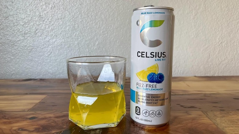 Can and glass of Fizz-Free Blue Razz Lemonade Celsius on a wooden tabletop