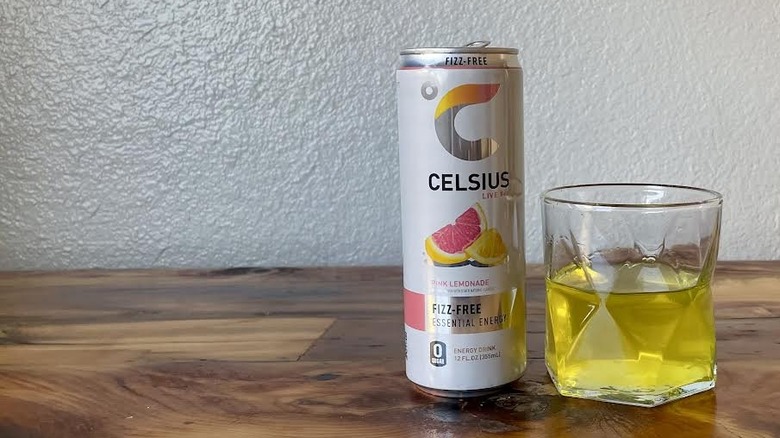 Can and glass of Fizz-Free Pink Lemonade Celsius on a wooden tabletop