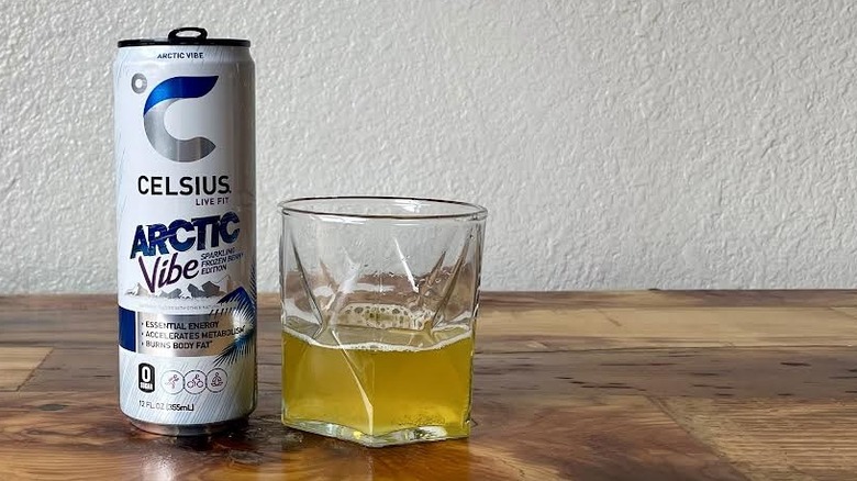 Can and glass of Arctic Vibe Sparkling Frozen Berry Celsius on a wooden tabletop