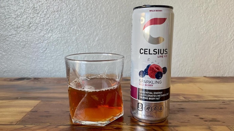 Can and glass of Sparkling Wild Berry Celsius on a wooden tabletop