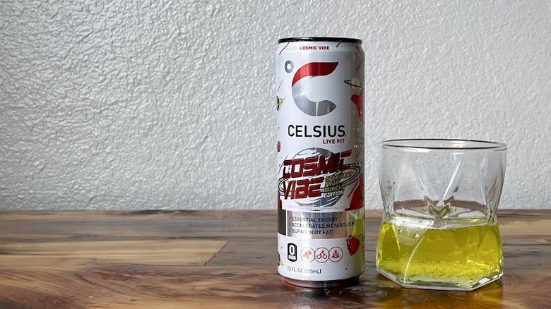 Can and glass of Cosmic Vibe Sparkling Fruit Punch Celsius on a wooden tabletop