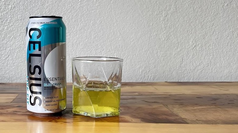 Can and glass of Essentials Blue Crush Celsius on a wooden tabletop