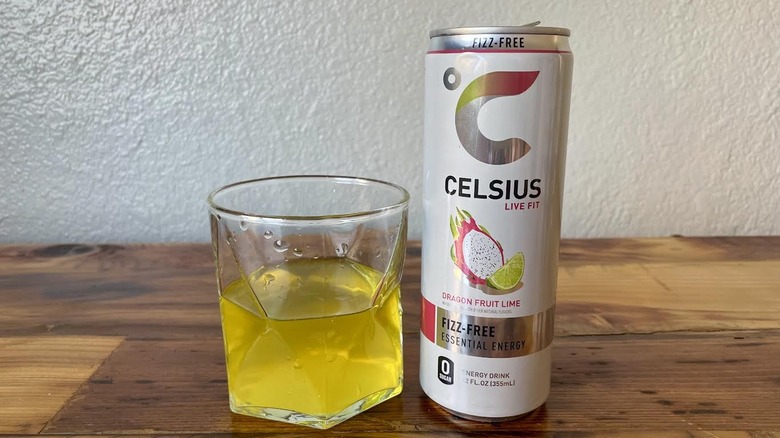 Can and glass of Fizz-Free Dragonfruit Lime Celsius on a wooden tabletop