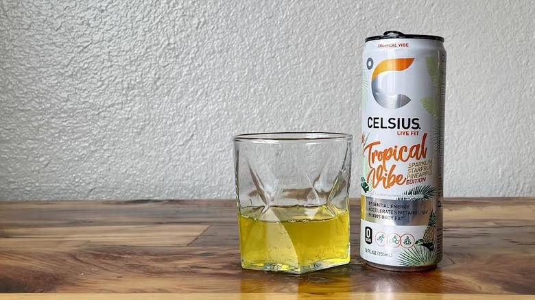 Can and glass of Tropical Vibe Sparkling Starfruit Pineapple Celsius on a wooden tabletop