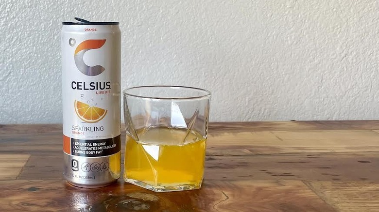 Can and glass of Sparkling Orange Celsius on a wooden tabletop