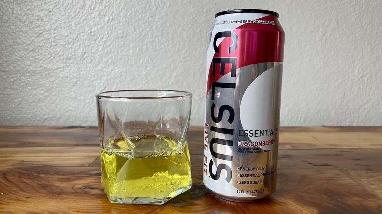 Can and glass of Essentials Dragonberry Celsius on a wooden tabletop