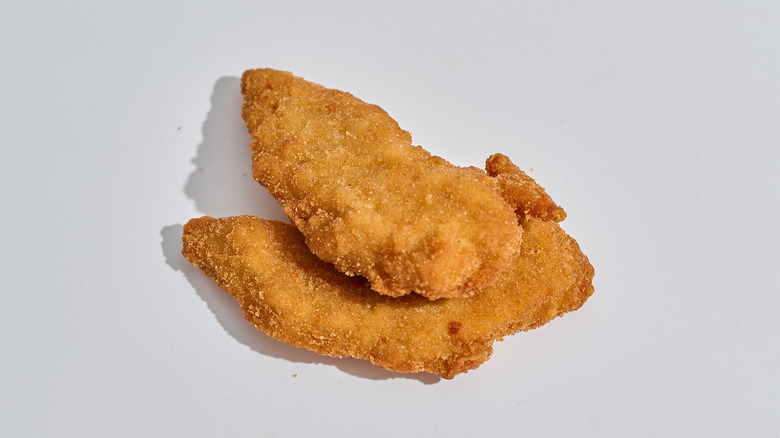 Crispy chicken tenders stacked on a table.