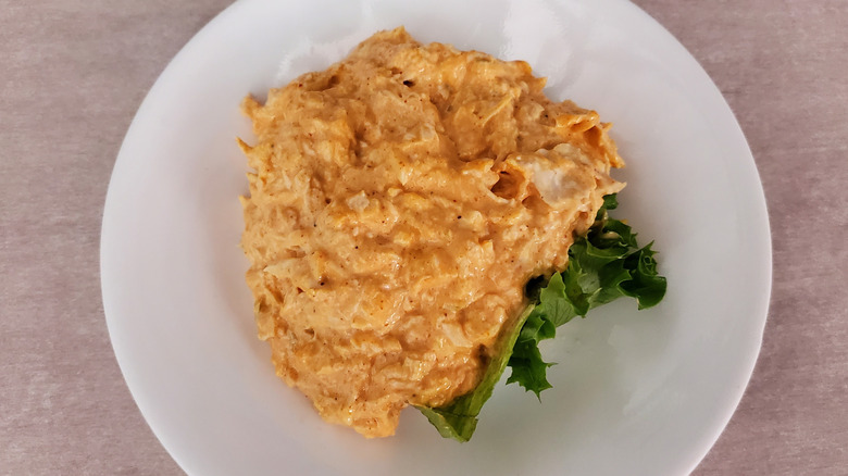 Buffalo Barclay chicken salad from Chicken Salad Chick on a lettuce leaf on a small, white plate