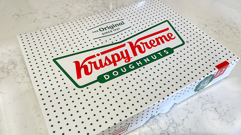 A closed Krispy Kreme donut box on a marble background