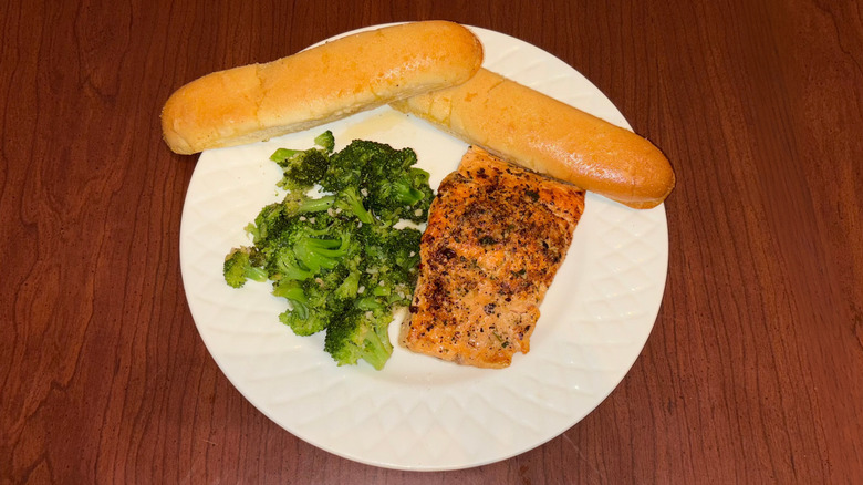 Herb-grilled salmon with broccoli and breadsticks.