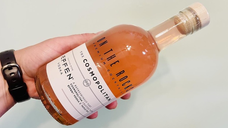 Hand holding bottle of On The Rocks Cosmopolitan