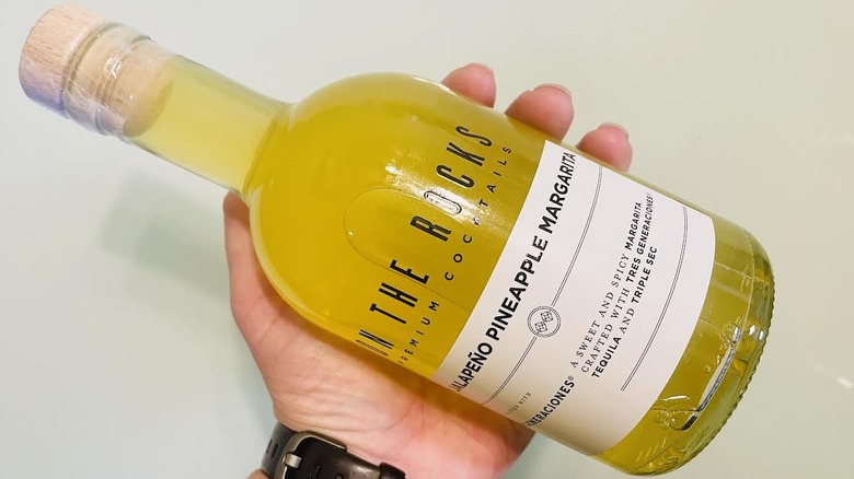Hand holding bottle of On The Rocks Jalapeño Pineapple Margarita