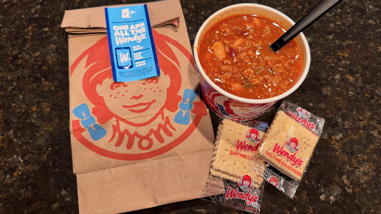 Cup of Wendy's chili and two packets of saltine crackers beside to-go baggie