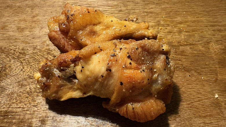 Two Lemon Pepper bone-in wings on brown wooden table