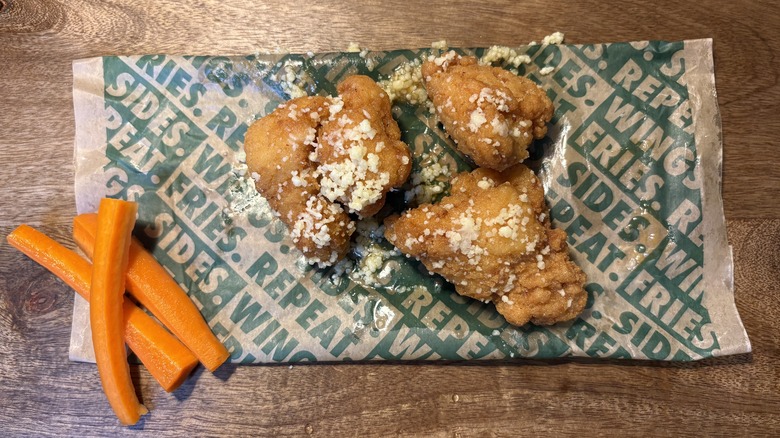 Three Garlic Parmesan boneless wings and carrots on Wingstop food paper
