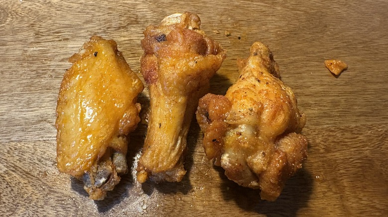 Three Hot Honey bone-in wings on brown wooden table