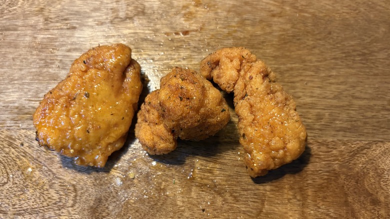 Three boneless Louisiana Rub wings on brown wooden table