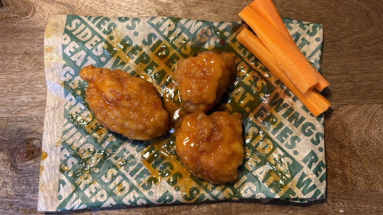 Three Mango Habanero boneless wings and carrots on Wingstop food paper