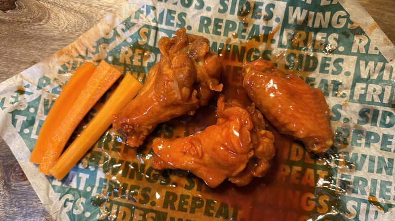 Three Original Hot bone-in wings and carrots on Wingstop food paper