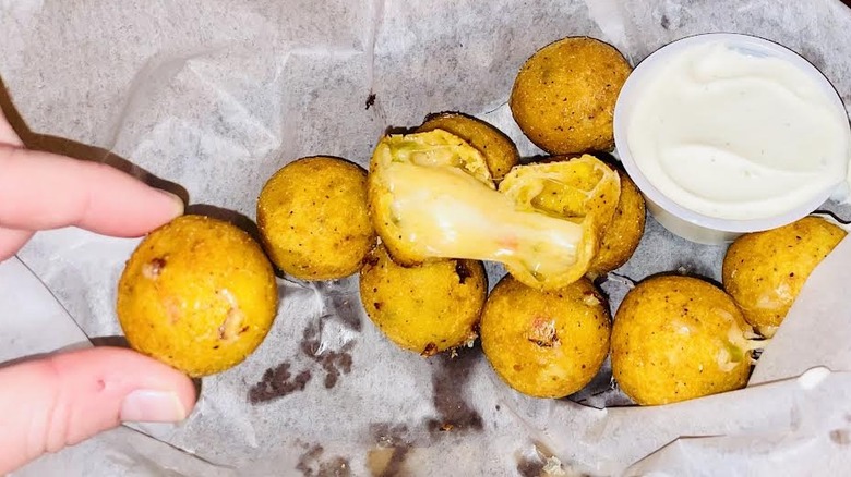 A hand grabs one of the Texas Roadhouse Rattlesnake Bites appetizer.