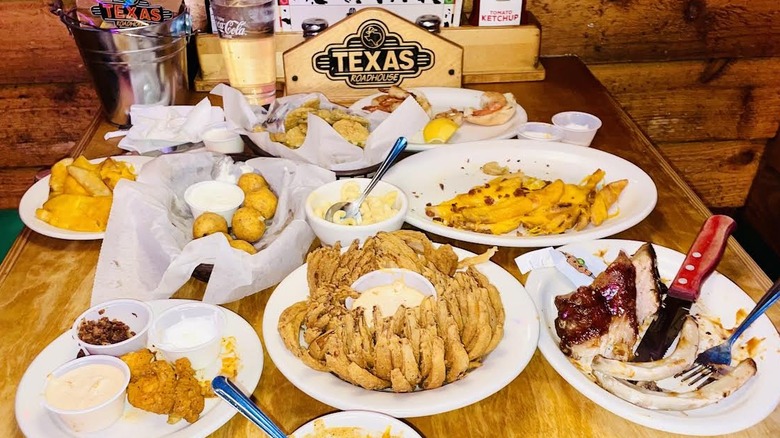 A table is full of partially eaten Texas Roadhouse appetizers.