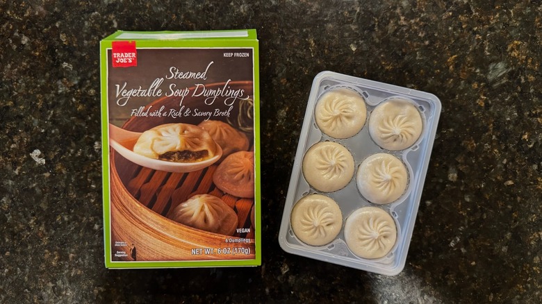 Box and bowl of Trader Joe's Steamed Vegetable Soup Dumplings on black counter