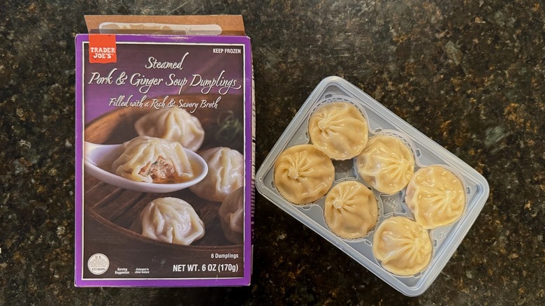Box and bowl of Trader Joe's Steamed Pork & Ginger Soup Dumplings on black counter